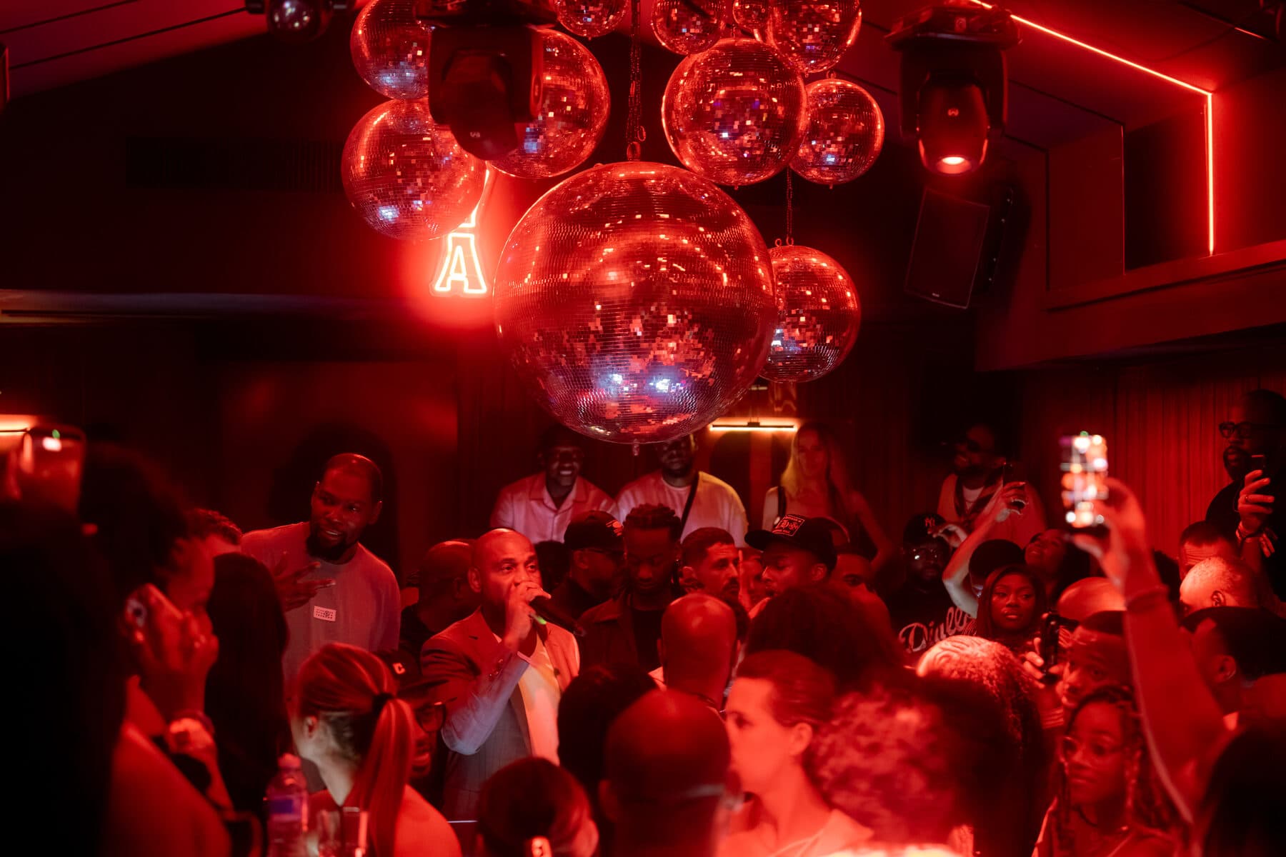 A packed room at a Culturin night, red lighting and neon signage